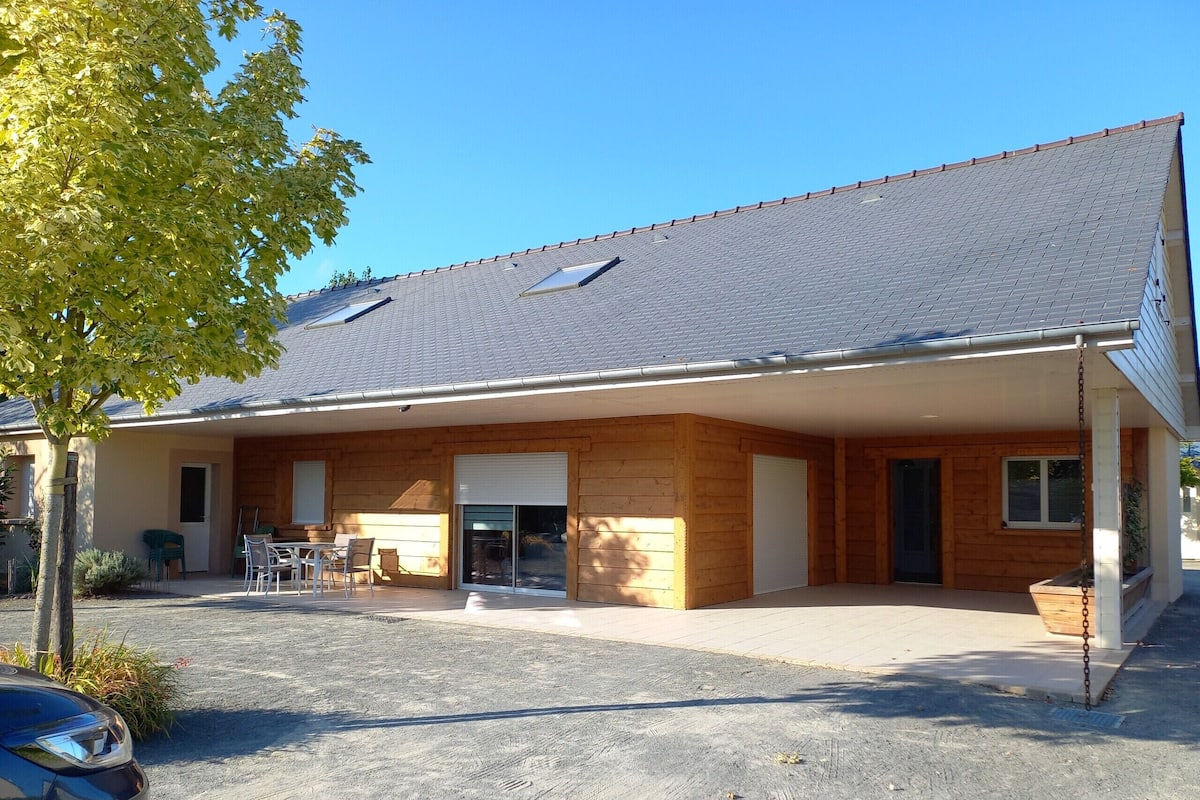 Un bâtiment à deux étages, doté d’un toit en pente, d’un patio couvert et d’une voiture garée devant.