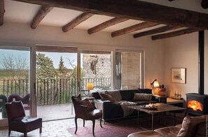 Relax in a cozy living room with a fireplace, comfortable seating area, and sliding glass door leading to a garden view.