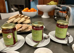 Una mesa con dos botes de mermelada de fresa de Kincardine Castle, un cuenco de naranjas y un plato de pan en rodajas.