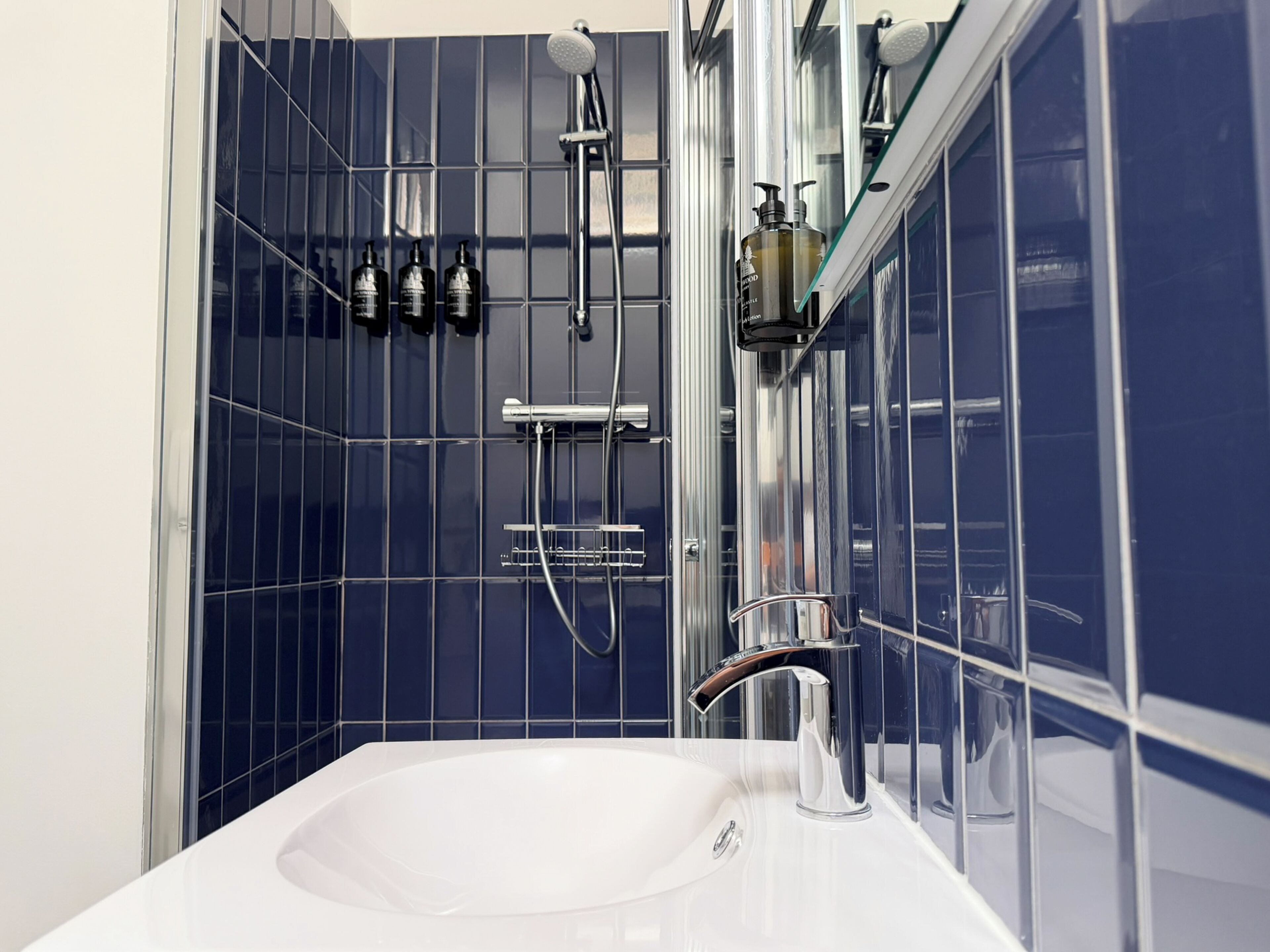A modern bathroom with a white sink, chrome fixtures, and blue-tiled walls.