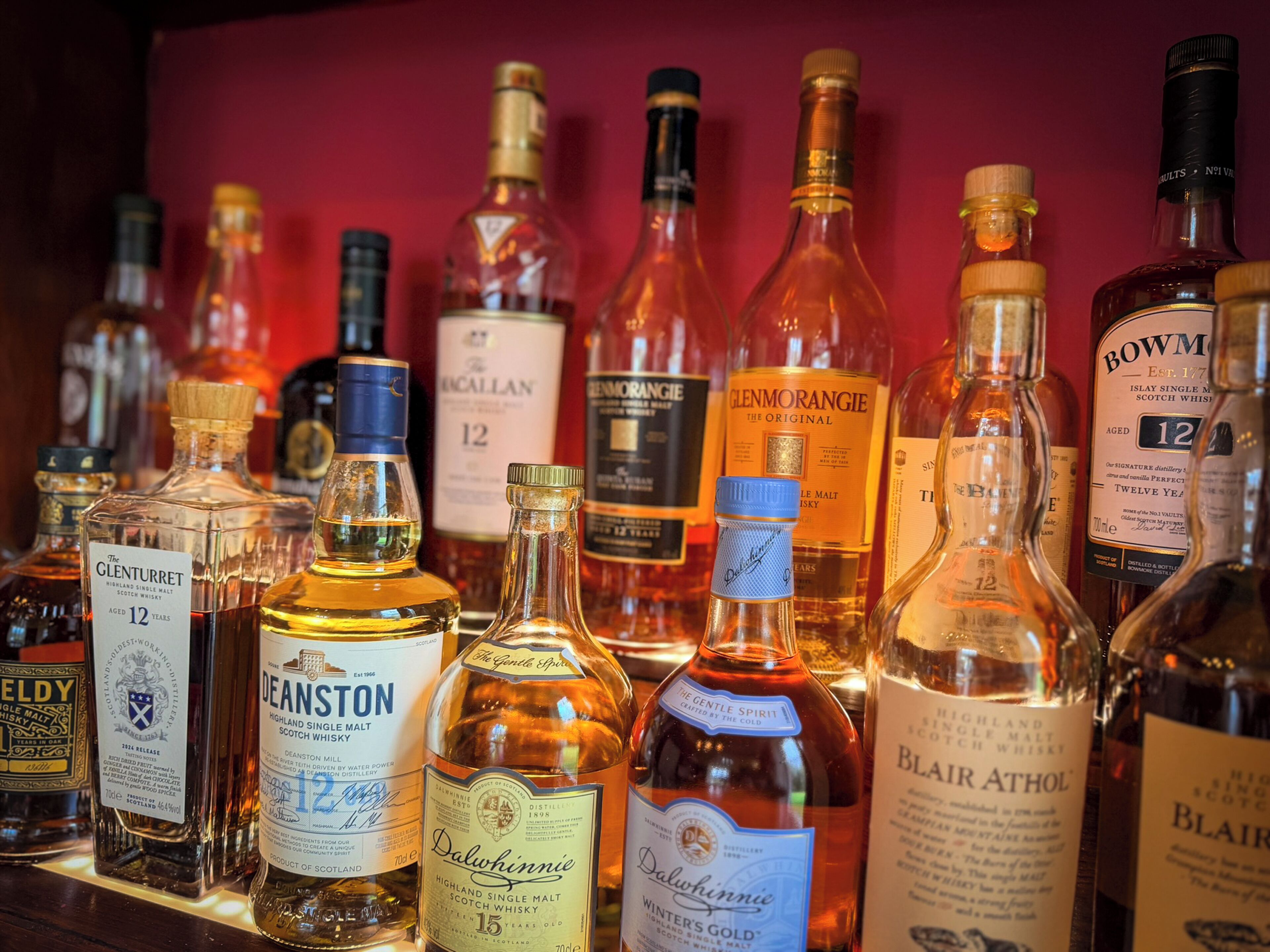 A variety of whisky bottles displayed on a shelf.