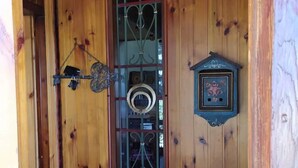 Une porte en bois avec un portail en métal, une petite boîte aux lettres et un objet décoratif accroché à la porte.