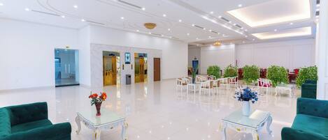 A spacious lobby with a high ceiling, polished floors, and green upholstered seating.