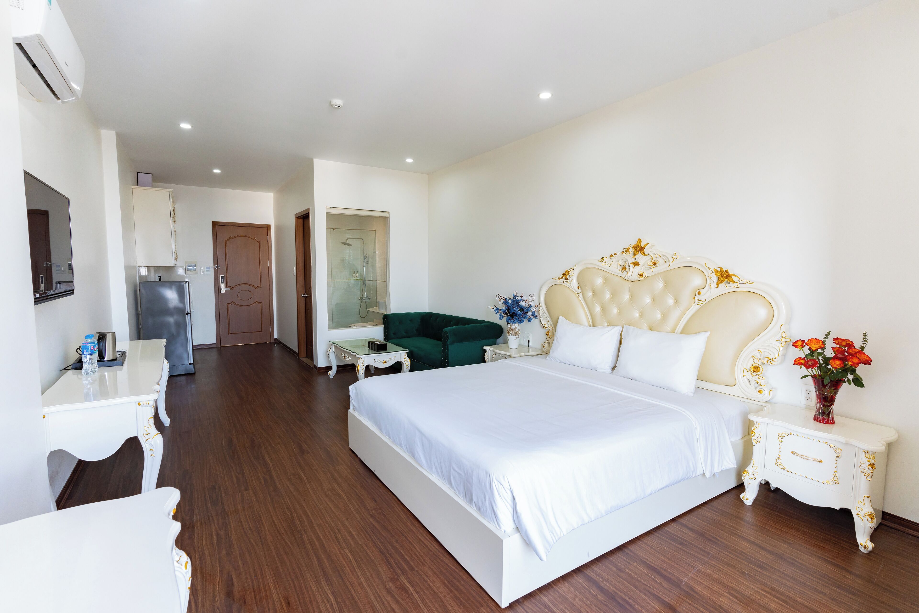 Quarto de hotel com uma cama grande, uma escrivaninha, uma cadeira, uma mesinha de apoio e um criado-mudo.