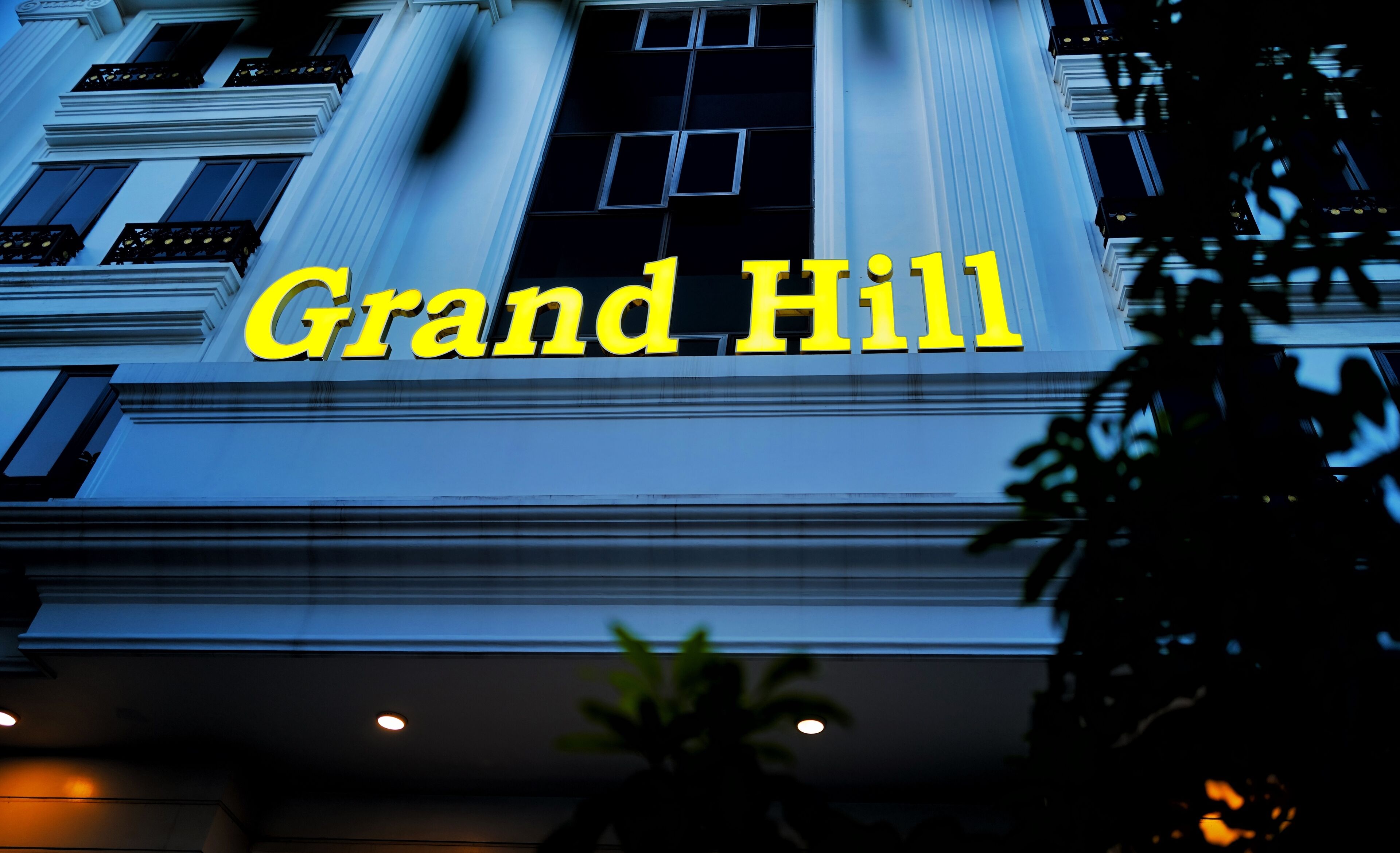 Facciata di un edificio con la scritta 'Grand Hill' in grandi lettere gialle.