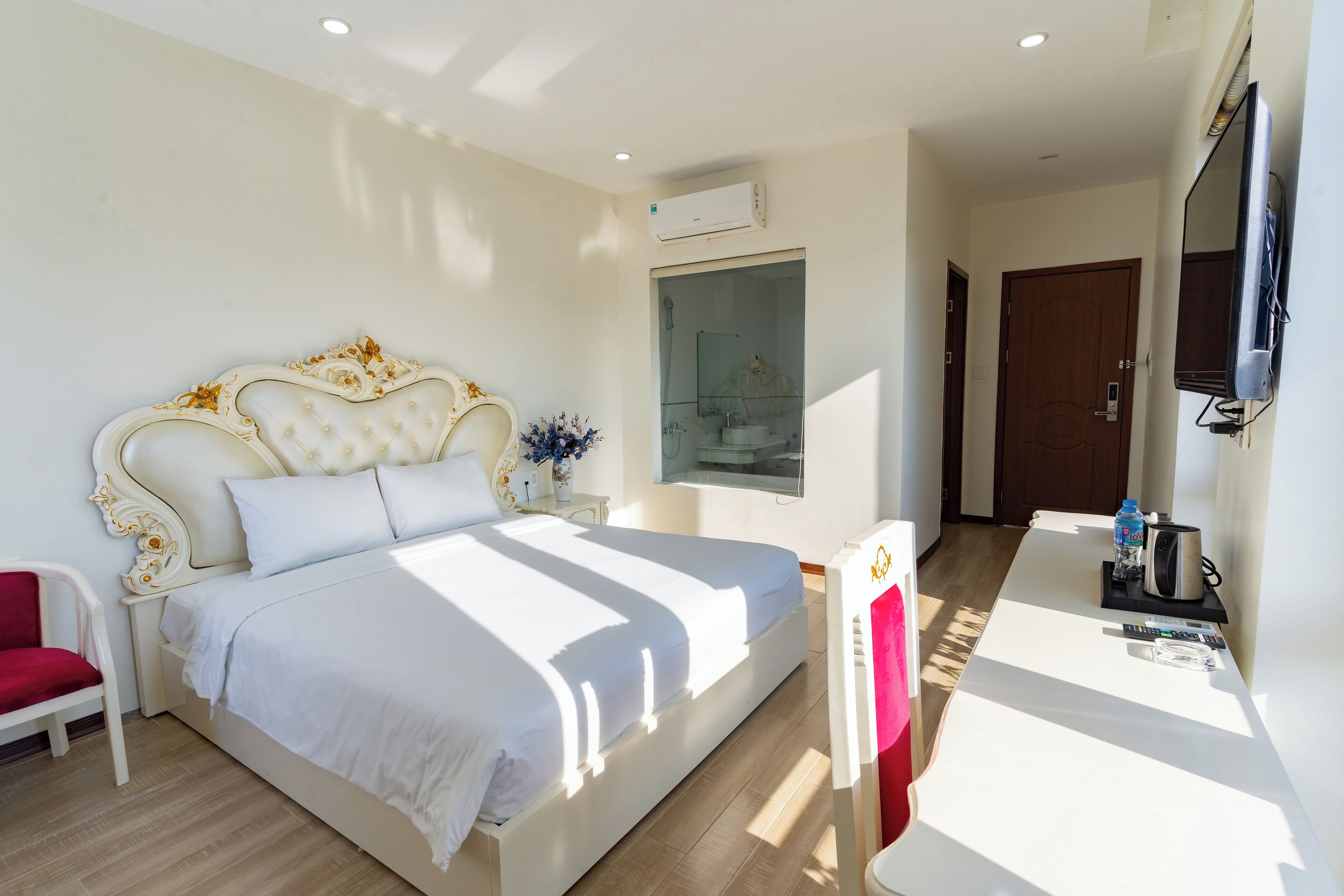 Una habitación de hotel con una cama grande, un escritorio, un televisor y un equipo de aire acondicionado.