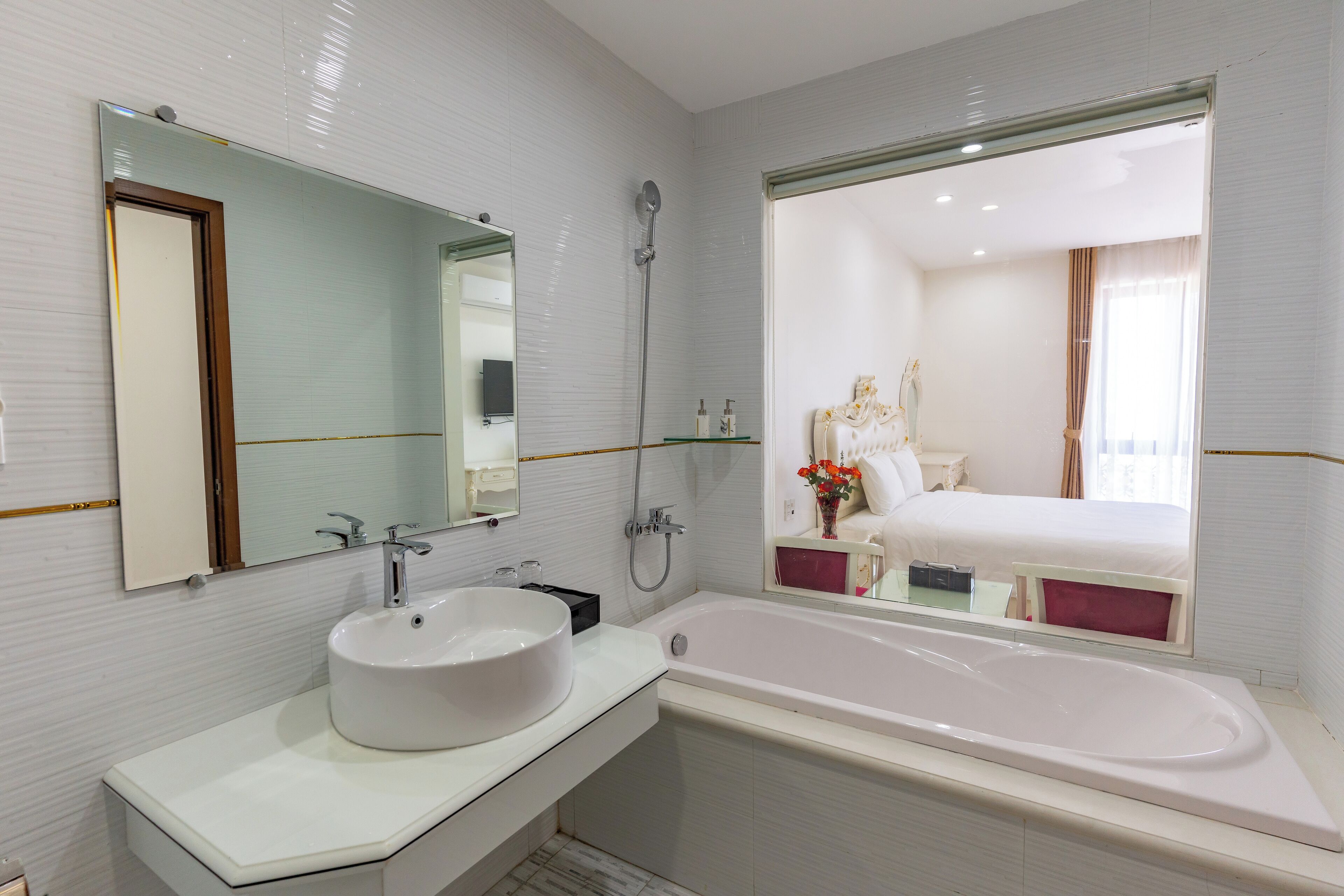 A modern bathroom with a large white bathtub, a round sink, and a shower.