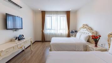 Quarto de hotel com duas camas, televisão, cómoda e janela com cortinas.