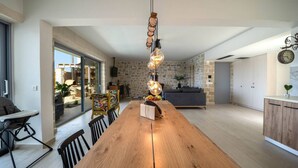 Eine moderne Küche mit einem Holzesstisch, Steinwänden und Blick in den angrenzenden Essbereich.