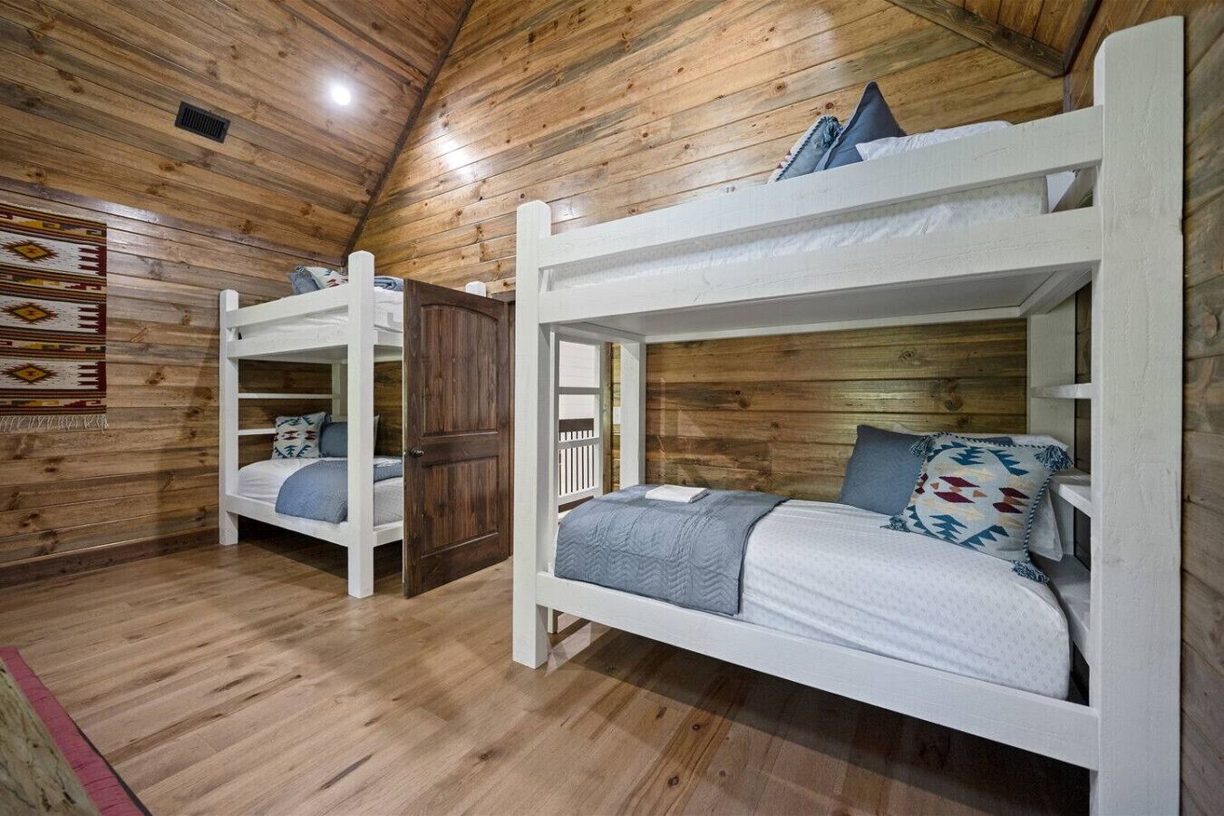 A cabin with two bunk beds, wooden walls, and a sloped ceiling.
