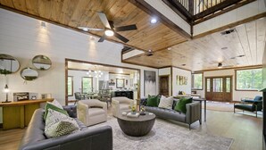 A spacious living room with a large gray sofa, a round coffee table, and a dining area with a wooden table and chairs. - New! Grand Hideaway| Secluded|6 Bedroom (Broken Bow)