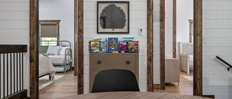 Une pièce avec un lit, un bureau avec des livres et un tableau encadré au mur.