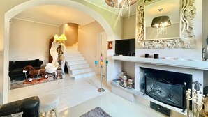 Una sala de estar con chimenea, televisor y escalera.