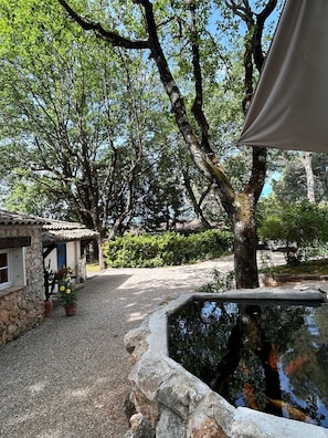 A stone building with a tiled roof, a gravel path, and a pond with koi fish. - Spacious Provencal villa in absolute calm. (Roquefort-les-Pins)