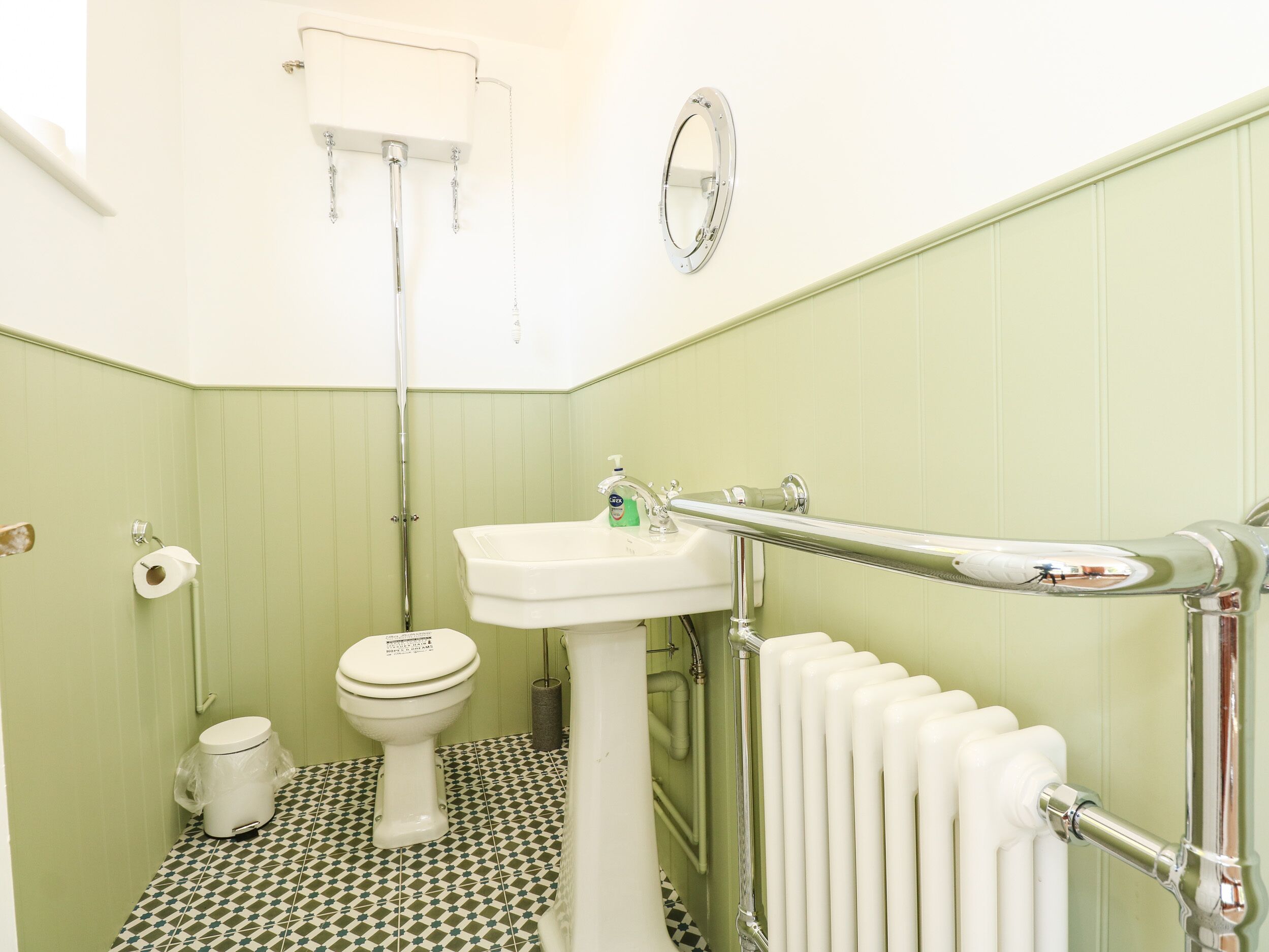 A bathroom with a toilet, sink, and radiator.