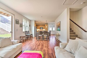 Uma sala de estar ampla com um sofá grande, uma mesa de centro e um espaço de refeições com cadeiras e mesa de madeira.