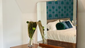 A wooden dresser with a mirror reflecting a bed with white bedding and green pillows. - Cozy and Charming Cottage in Kerhonkson (Kerhonkson)