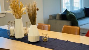 A dining table with two white vases containing dried plants, a candle, and a gold-rimmed glass. A dark blue cloth covers the table. - Cozy and Charming Cottage in Kerhonkson (Kerhonkson)
