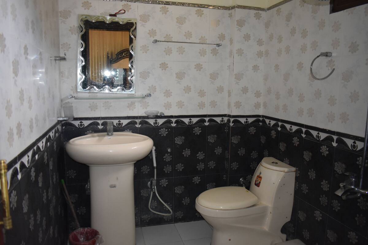 Un baño con lavamanos, inodoro y espejo sobre el lavamanos.