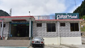 A hotel with a brick facade and a sign indicating 24-hour service. - Clifton Hotel (Balakot)
