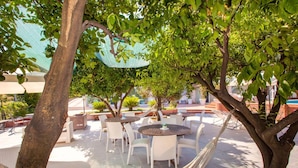 An outdoor seating area with white chairs and tables, surrounded by trees and a hammock. - Villa Amore in Castellammare di Stabia (Castellammare di Stabia)