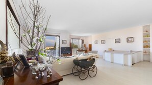 A spacious living room with a large window, a wooden coffee table, and a sofa. There is a white cabinet with shelves and a small table with decorative items. - Villa Amore in Castellammare di Stabia (Castellammare di Stabia)