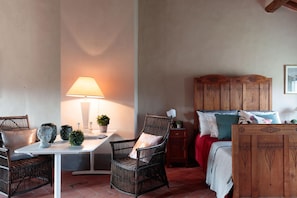 Une pièce confortable avec un lit, une tête de lit en bois, une table avec une lampe et des chaises en osier.