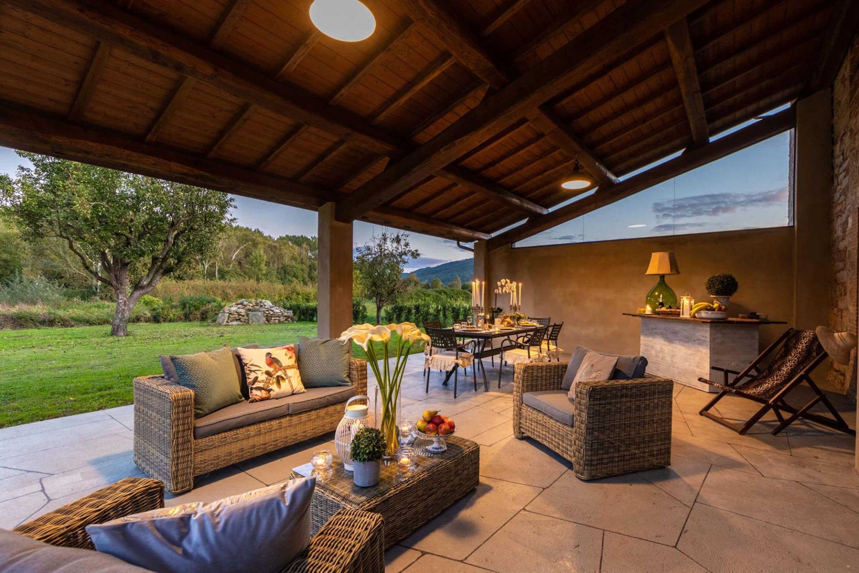 An outdoor patio area with wicker furniture, a dining table, and a view of the surrounding landscape.