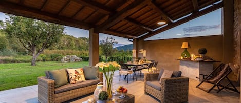 An outdoor patio area with wicker furniture, a dining table, and a view of the surrounding landscape.