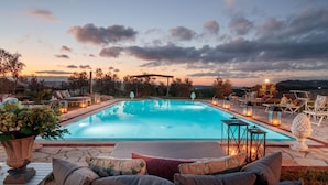 Une piscine rectangulaire entourée d’une terrasse, de chaises longues et dotée d’un éclairage extérieur.