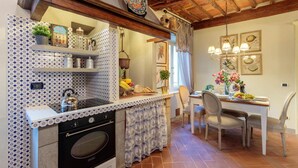 A kitchen with a built-in oven, a sink, and a dining area with a table and chairs. - Casa Kathy in Lucca With 2 Bedrooms and 1 Bathrooms (Lucca)