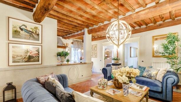A spacious living room with a high wooden ceiling, a blue sofa, a wooden coffee table, and a chandelier. - Casa Kathy in Lucca With 2 Bedrooms and 1 Bathrooms (Lucca)