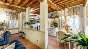 A cozy living area with a sofa, a dining table with chairs, and a kitchen area with a counter and various items. - Casa Kathy in Lucca With 2 Bedrooms and 1 Bathrooms (Lucca)