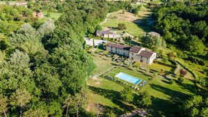 An aerial view of a residential area with a large house, a swimming pool, and surrounding greenery. - Villa Hilary in Lucca (Lucca)