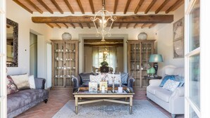 A cozy living room with a wooden ceiling, two sofas, a coffee table, and a chandelier. - Villa Hilary in Lucca (Lucca)