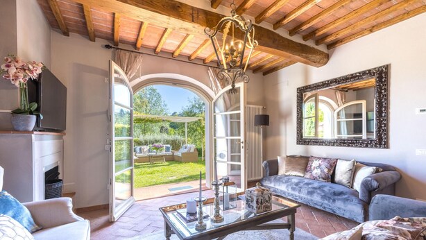 A spacious living room with a large window, a sofa, a coffee table, and a fireplace. - Villa Hilary in Lucca (Lucca)