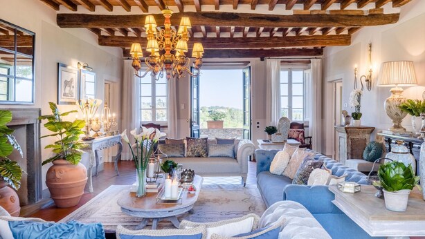A spacious living room with a high wooden ceiling, a large chandelier, and a comfortable seating area with sofas and a coffee table. - Fattoria Camigliano Wine Estate (Capannori)