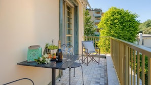 Een balkon met een tafel, stoelen en een fles wijn.