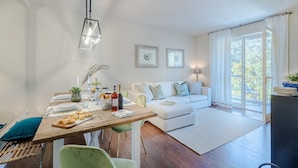 Een moderne woonkamer met een eethoek, witte muren en een groot raam.