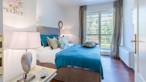 Een slaapkamer met een bed, nachtkastje, lamp en een raam met gordijnen.