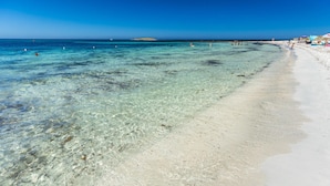 A beach with clear shallow waters, a sandy shore, and a distant island. - Villa La Bella in Ottiolu (Budoni)