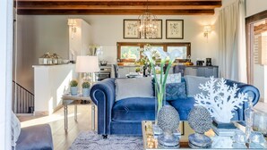 A modern living room with a blue sofa, a coffee table with decorative items, and a kitchen in the background. - The Luxury Beach Villa (Viareggio)