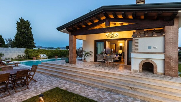 A covered patio with a pool, outdoor seating, and a fireplace. - The Luxury Beach Villa (Viareggio)