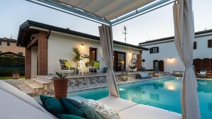 A poolside area with a covered seating area, a small pool, and a brick wall. - The Luxury Beach Villa (Viareggio)