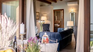 A modern living room with a dark blue sofa, a glass door leading to an outdoor area, and a wooden ceiling. - The Luxury Beach Villa (Viareggio)