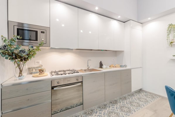 A modern kitchen with white cabinets, a built-in microwave, a gas stove, and a sink.