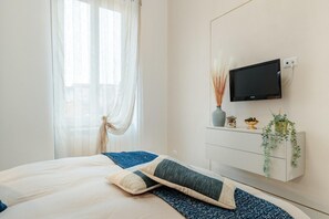 A modern bedroom with a bed, a mounted TV, and a bedside table with decorative items.