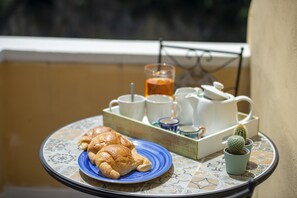 A breakfast tray with croissants, coffee cups, a teapot, and a cactus on a table. - Amore Rentals - Casa Barbera A (Positano)