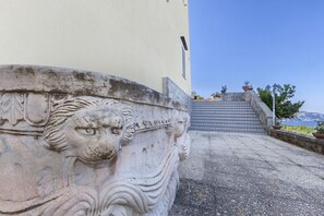 A stone staircase leading to a building entrance with a lion head relief.