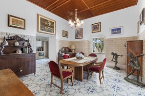 A dining area with a wooden table and chairs, a chandelier, and artwork on the walls.